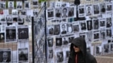 Мужчина проходит мимо портретов белорусских политзаключенных. Уличная выставка в Варшаве. Май 2025 года
